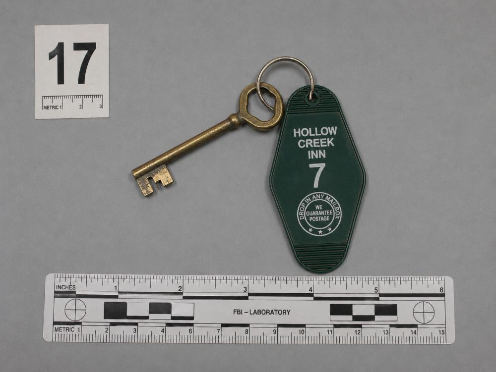 Evidence photograph of a brass key and green Hollow Creek Inn Room 7 key tag